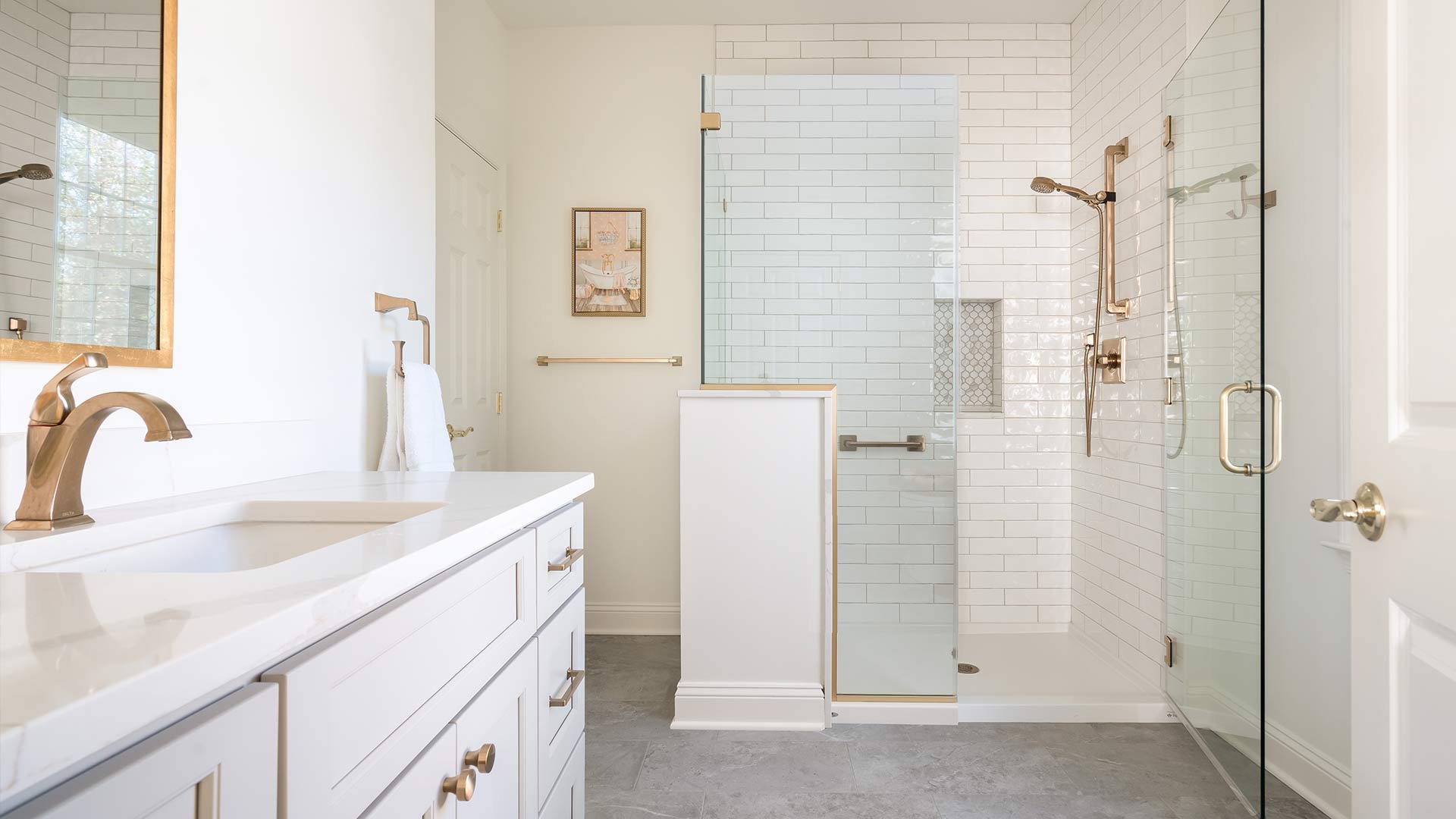 high end remodeled bathroom with white tile and gold accents